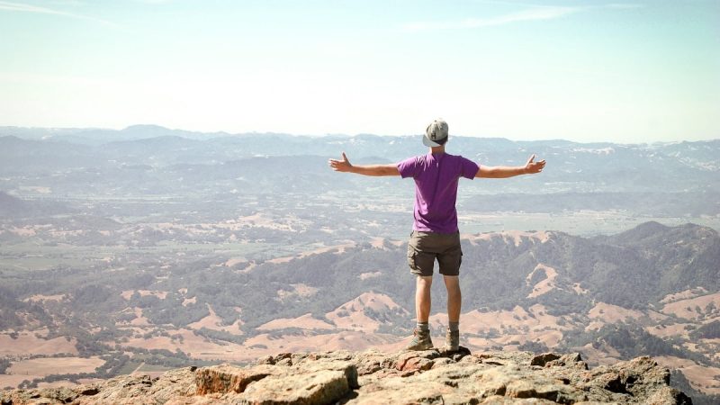 man stand on brown mountain under blue sky